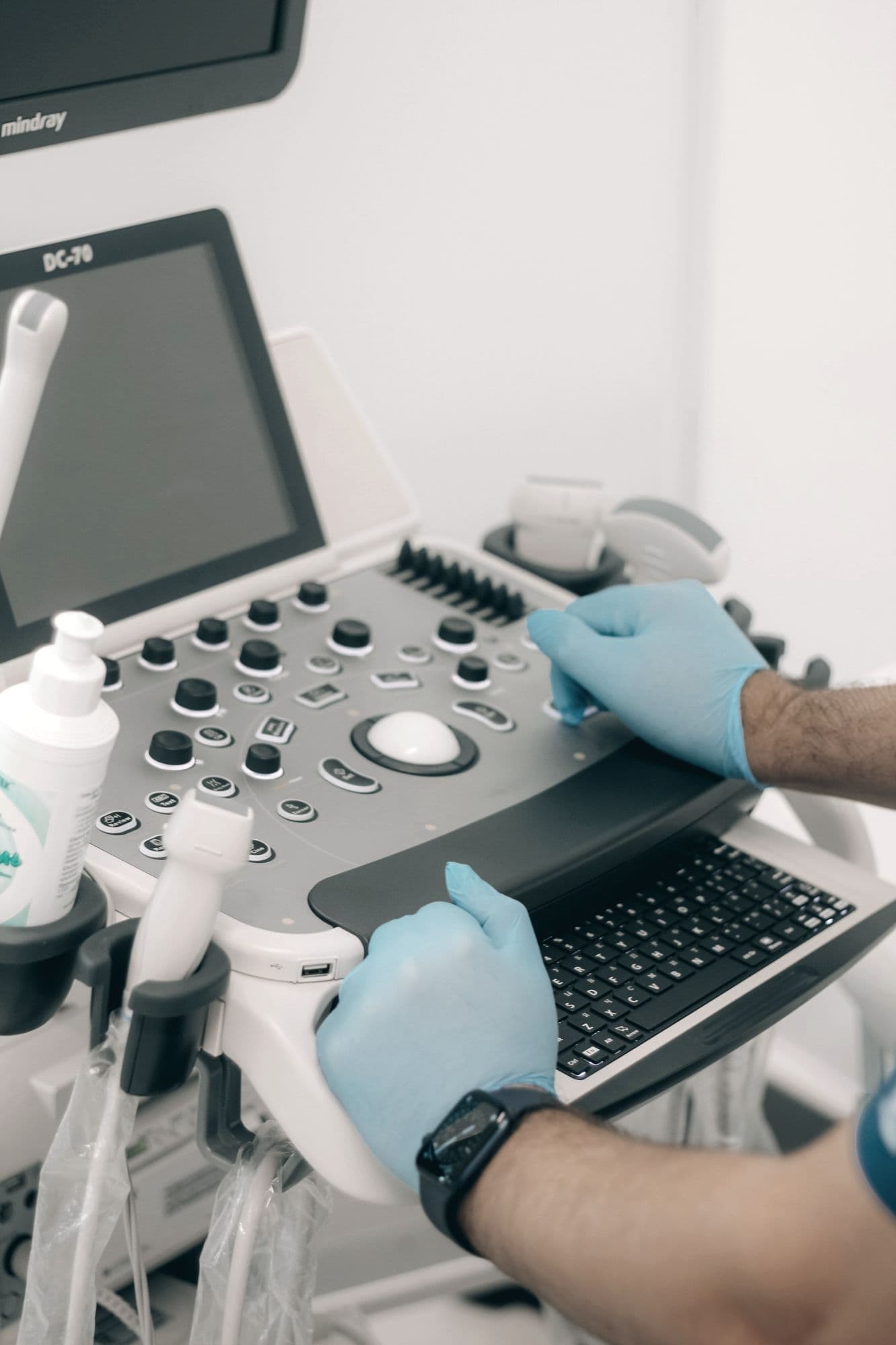 Gloved hands working the controls of an ultrasound machine